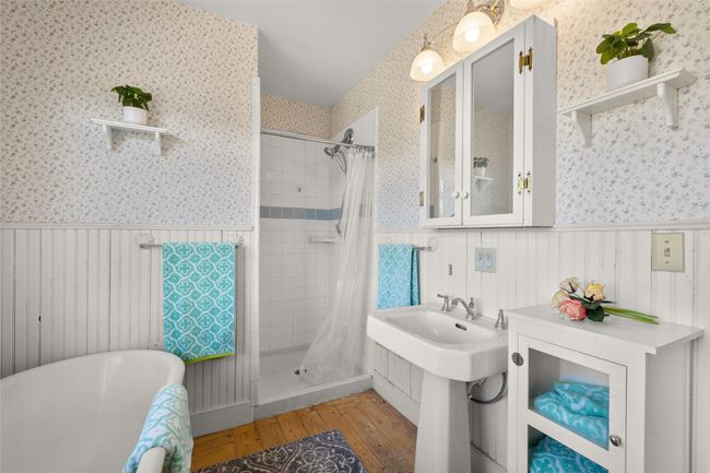 Bathroom with wallpapered walls, hardwood / wood-style floors, a shower stall, and wainscoting | Image 21