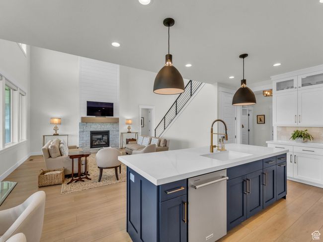 Kitchen with dishwasher, a sink, white cabinetry, open floor plan, and light wood finished floors | Image 17