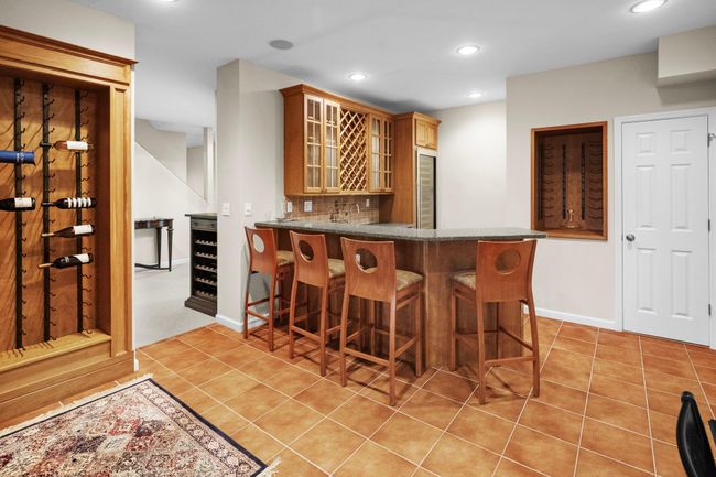 The custom wet bar is an entertainer’s dream with granite counters, glass cabinetry, wine racks, and bar seating for four. | Image 39