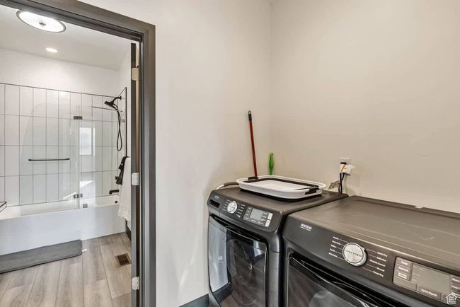 Laundry room with laundry area, independent washer and dryer, and wood finished floors | Image 37