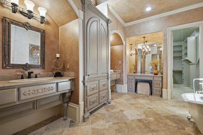 The primary bath has separate vanities, a dressing area, a custom closet, claw foot tub, and luxurious walk in shower. | Image 21