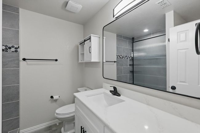Full bathroom with toilet, vanity, baseboards, wood finished floors, and a shower | Image 27