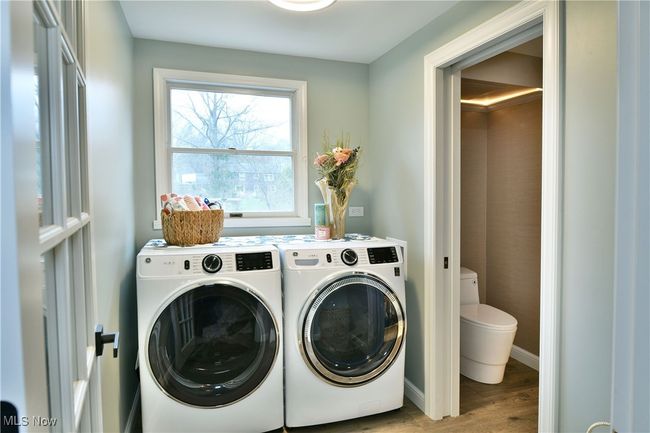 Laundry area featuring washing machine and dryer, laundry area, baseboards, and wood finished floors | Image 22