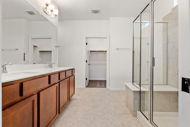 Full bathroom featuring a walk in closet, a shower stall, and double vanity | Image 10