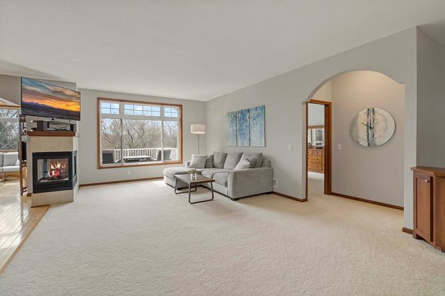 A three-sided gas-burning fireplace, large living space, and main level primary suite is tucked into the right of the photo. | Image 5