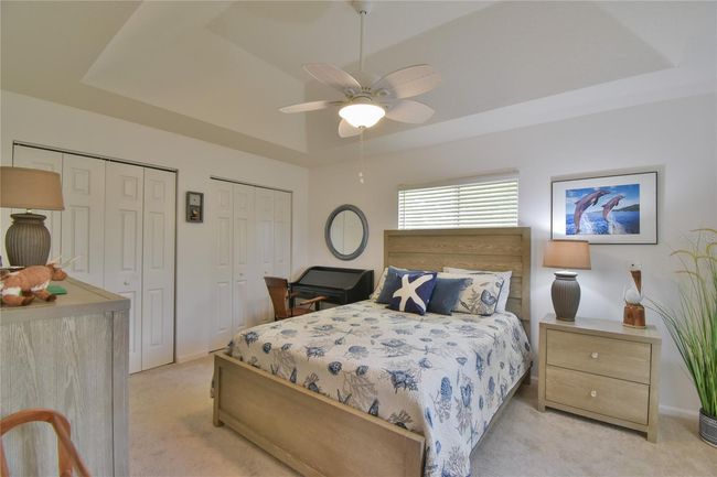 Guest Bedroom with Full Length Closet and view of the golf course with Tray Ceiling with fan and light | Image 16