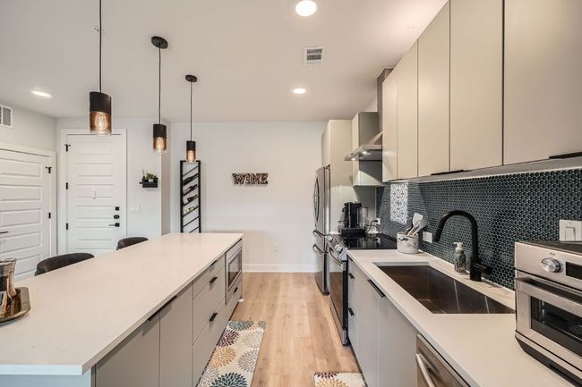 Kitchen featuring appliances with stainless steel finishes, light wood-style floors, a kitchen island, decorative light fixtures, and recessed lighting | Image 9
