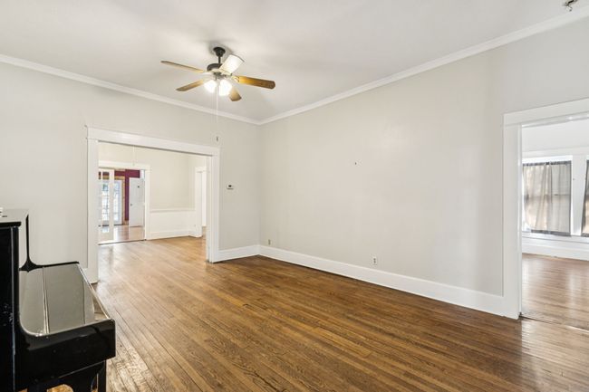 Unfurnished living room featuring a ceiling fan, hardwood / wood-style floors, ornamental molding, and baseboards | Image 5