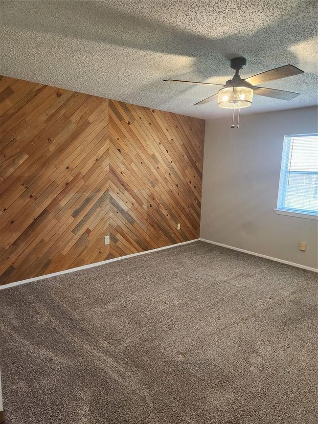 Carpeted spare room with ceiling fan, wood walls, and baseboards | Image 19