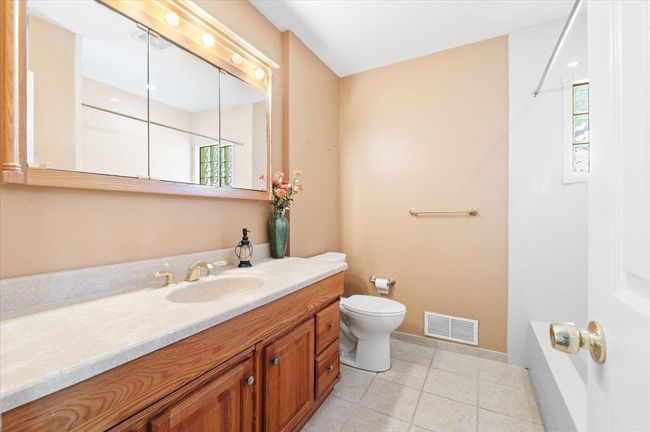 Bathroom featuring vanity, a healthy amount of sunlight, tile patterned floors, and toilet | Image 14