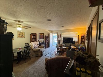 Carpeted living room with a textured ceiling and ceiling fan | Image 3