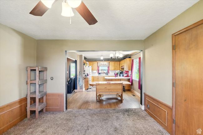 Playroom featuring light colored carpet, a wainscoted wall, ceiling fan, a textured ceiling, and a chandelier | Image 7