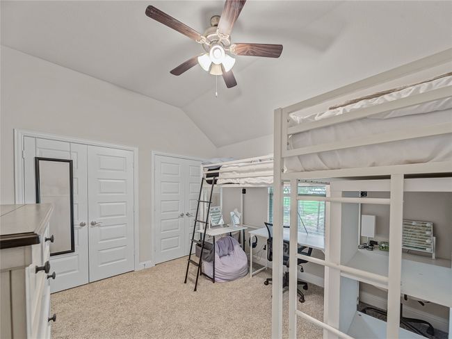 Bedroom featuring multiple closets, an office area, carpet floors, vaulted ceiling, and ceiling fan | Image 27
