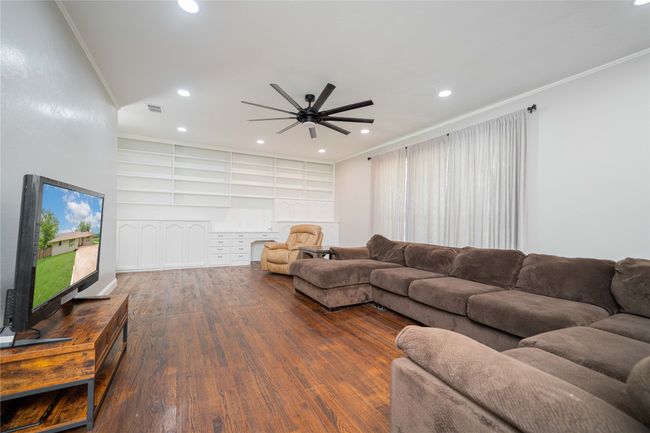 Living area featuring wood finished floors, a ceiling fan, recessed lighting, built in shelves, and ornamental molding | Image 10
