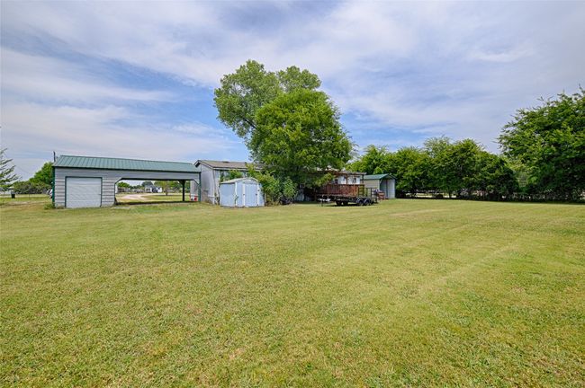View of green lawn with a storage unit and a carport | Image 24