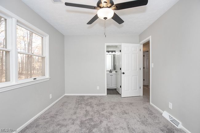 Unfurnished bedroom featuring ensuite bathroom, ceiling fan, and light carpet | Image 16