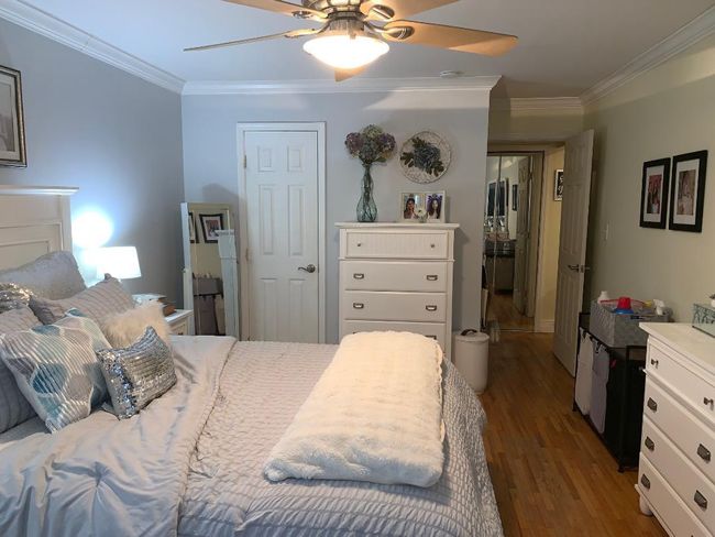 Bedroom crown molding, wood finished floors, ceiling fan, and two closets | Image 11
