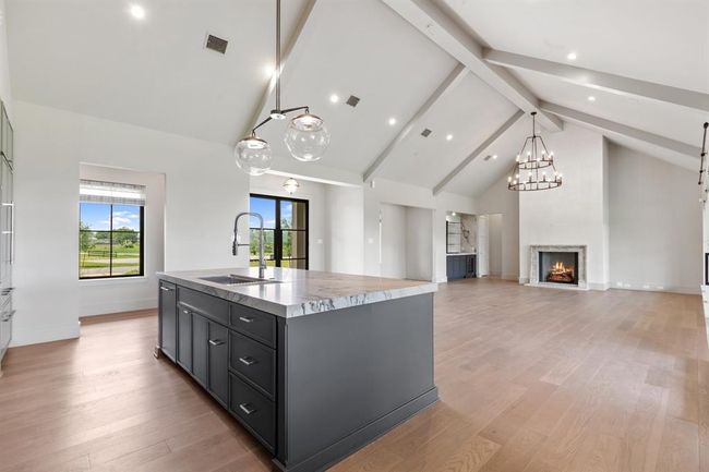 The dramatic vaulted ceilings create abundant volume and the beams add architectural interest to the open concept family room and kitchen. | Image 7