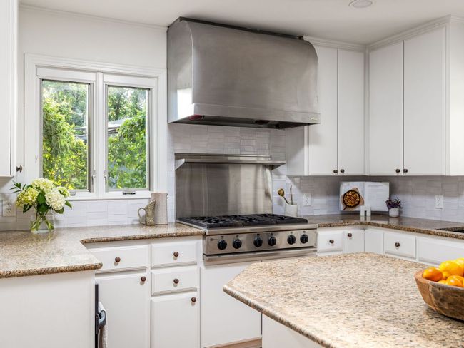 Kitchen with stainless steel refrigerator, kitchen island, & backsplash. | Image 11