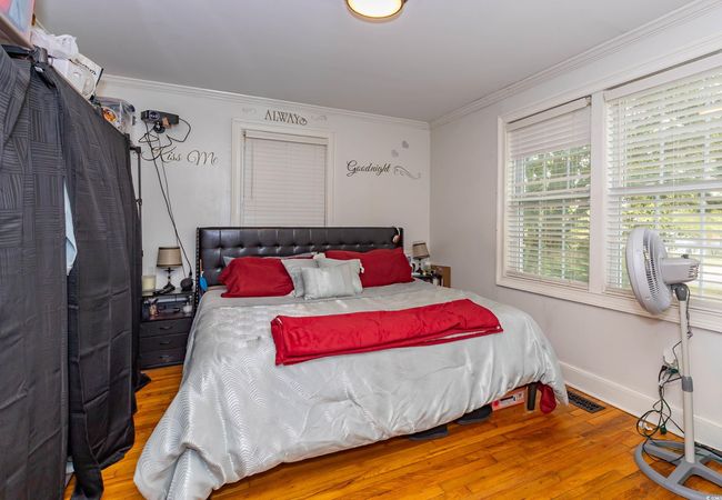 Bedroom with crown molding, baseboards, visible vents, and hardwood / wood-style flooring | Image 7