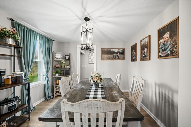 Dining area with wood finished floors, a notable chandelier, and baseboards | Image 5