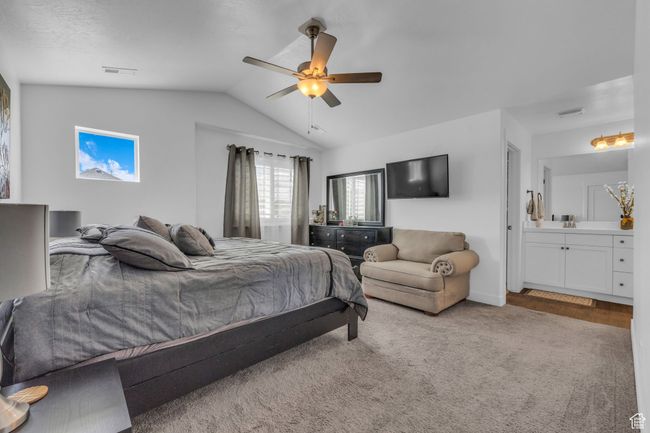 Primary bedroom featuring vaulted ceiling, ceiling fan, carpet floors, and connected bathroom | Image 12