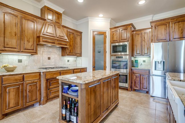 Kitchen featuring brown cabinets, light stone counters, and stainless steel appliances | Image 11