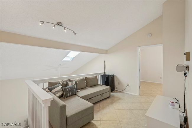 Living area with vaulted ceiling, a skylight, and light tile patterned floors | Image 22