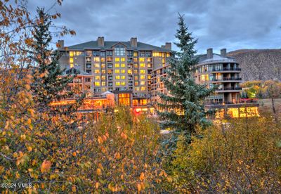 Admire the hotel’s exterior adorned in vibrant fall colors, creating a picturesque scene that perfectly complements the stunning natural surroundings and invites you to enjoy the beauty of the season. | Image 1