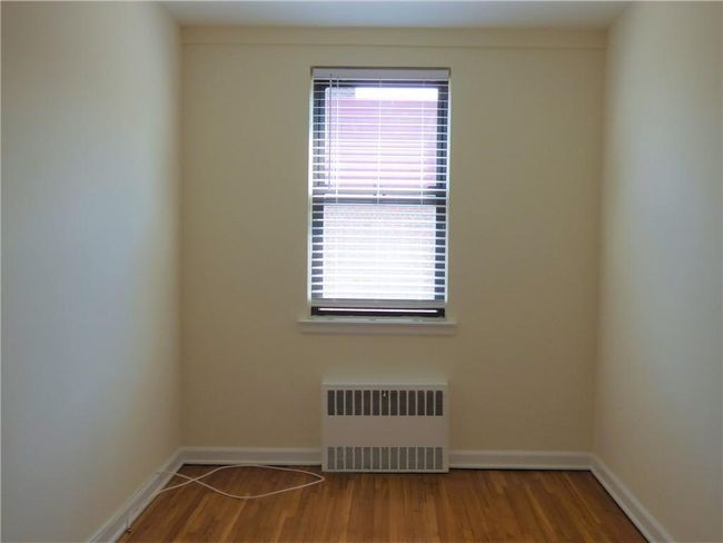 Bedroom room featuring radiator, wood finished floors, and baseboards | Image 13
