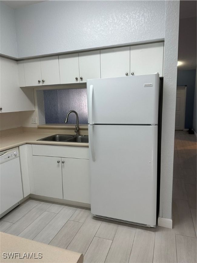 Kitchen featuring sink, white cabinetry, dishwashing machine, and white refrigerator | Image 7
