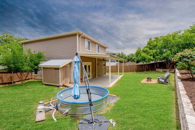 Fenced backyard featuring a fire pit, a shed, and a patio | Image 28