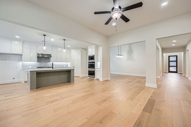 Kitchen with light countertops, tasteful backsplash, light wood-style flooring, stainless steel appliances, and white cabinets | Image 6