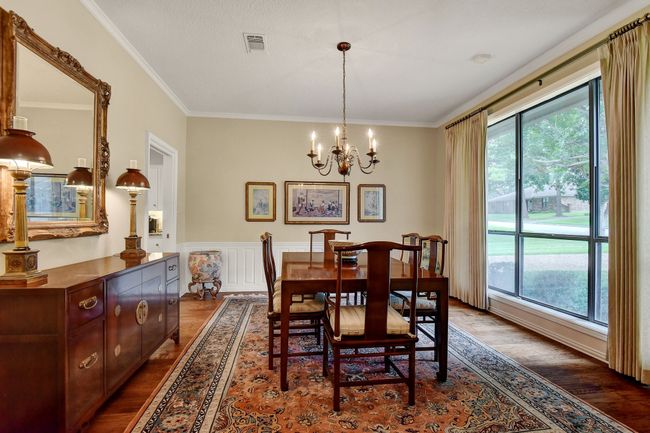 Dining area with healthy amount of natural light, a chandelier, dark wood-style flooring, crown molding, and wainscoting | Image 7