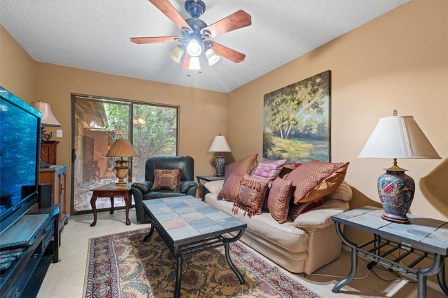 Living room with a textured ceiling, light colored carpet, and ceiling fan | Image 24