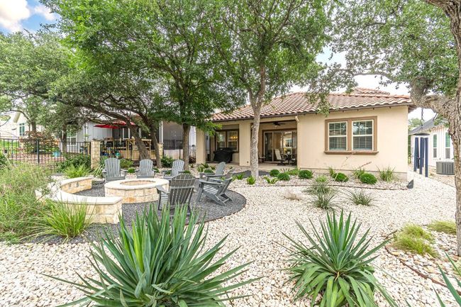 Rear view of property featuring a ceiling fan, an outdoor fire pit, central AC, stucco siding, and a tile roof | Image 39
