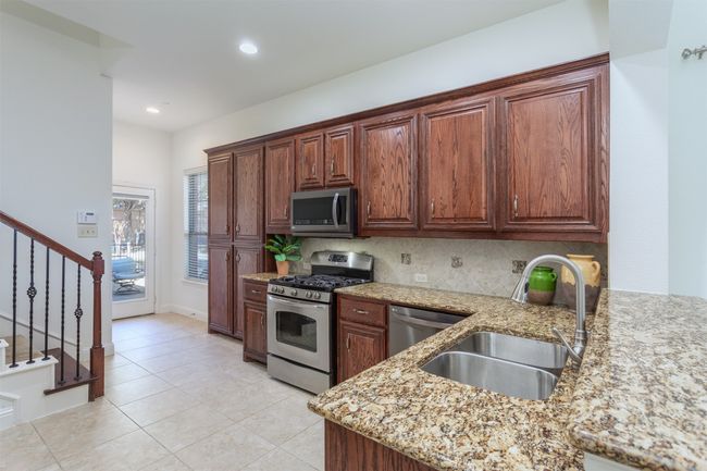 Kitchen with backsplash, light stone counters, recessed lighting, appliances with stainless steel finishes, and a sink | Image 11