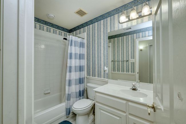 Full bathroom featuring shower / bath combo, toilet, visible vents, wallpapered walls, and vanity | Image 22