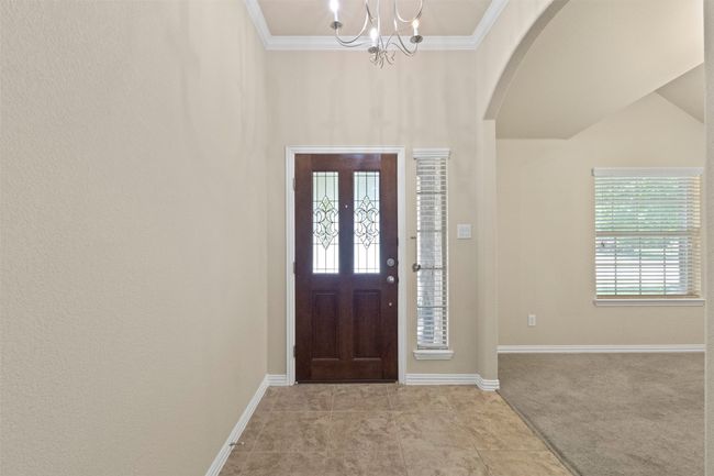 Carpeted entrance foyer with arched walkways, a chandelier, and crown molding | Image 7