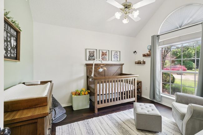 Bedroom with vaulted ceiling, a nursery area, multiple windows, and wood finished floors | Image 28