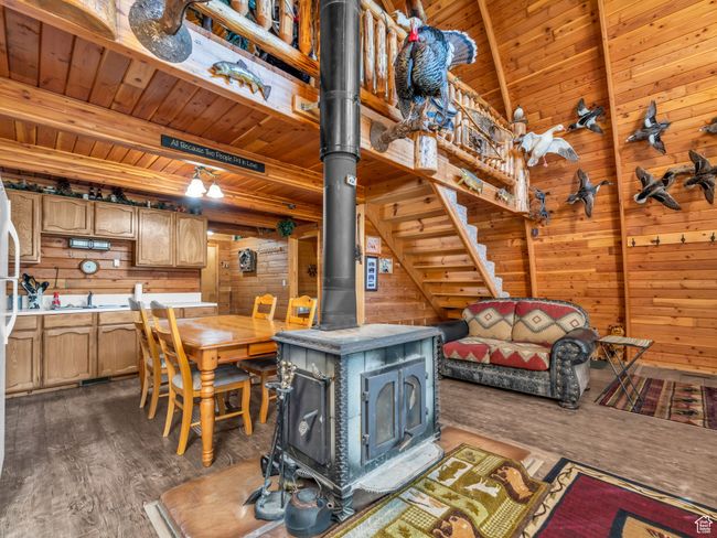 Kitchen featuring a wood stove, wooden walls, a wood ceiling with exposed beams, dark wood-style flooring, and light countertops | Image 8