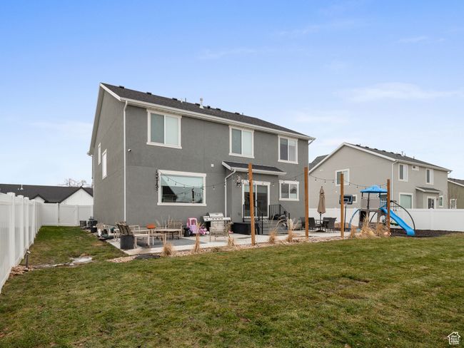 Rear view of property with a playground, a patio area, a fenced backyard, and stucco siding | Image 9