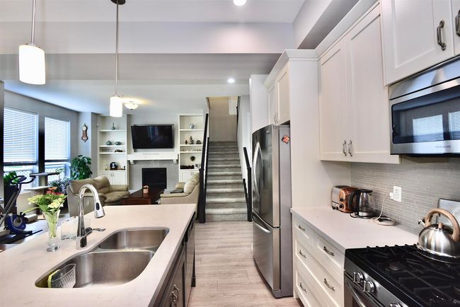 Kitchen with appliances with stainless steel finishes, white cabinetry, light wood finished floors, open floor plan, and a fireplace | Image 15