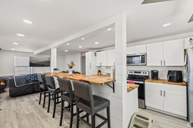 Kitchen featuring wooden counters, appliances with stainless steel finishes, recessed lighting, white cabinets, and light wood-style floors | Image 8
