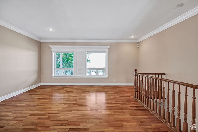 Empty room with light wood-type flooring, baseboards, crown molding, and recessed lighting | Image 6
