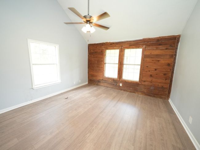 Unfurnished room featuring a ceiling fan, light wood-type flooring, wooden walls, and high vaulted ceiling | Image 16