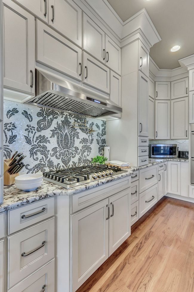 Custom tiled feature behind the gas range. | Image 19