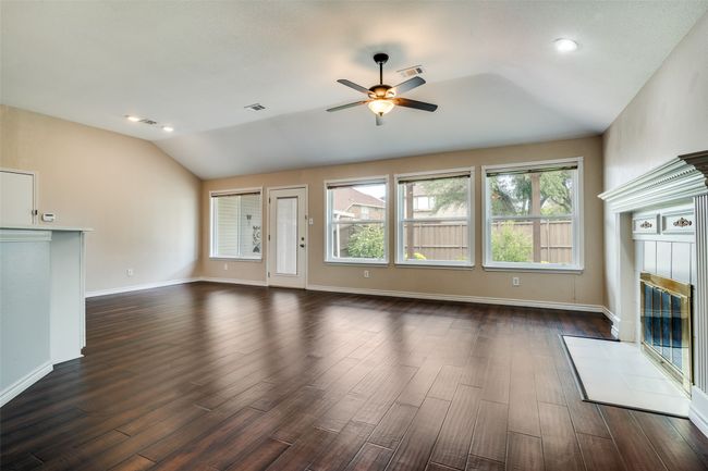 Unfurnished living room with vaulted ceiling, a tiled fireplace, dark wood-type flooring, ceiling fan, and recessed lighting | Image 12