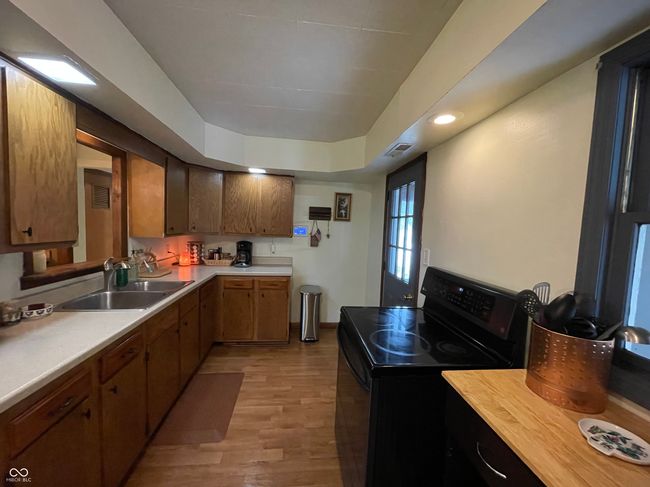 kitchen featuring black range with electric cooktop, light countertops, light wood-style flooring, recessed lighting, and a raised ceiling | Image 10