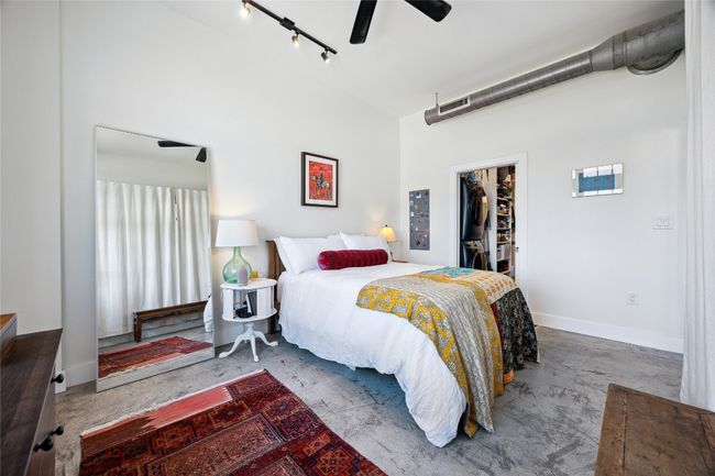 Bedroom featuring a spacious closet, concrete flooring, a closet, and a ceiling fan | Image 15